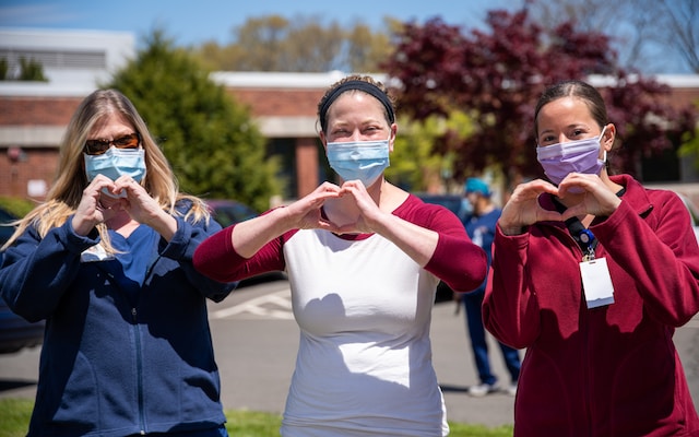 3 nursing home employees making hearts with their hands. 